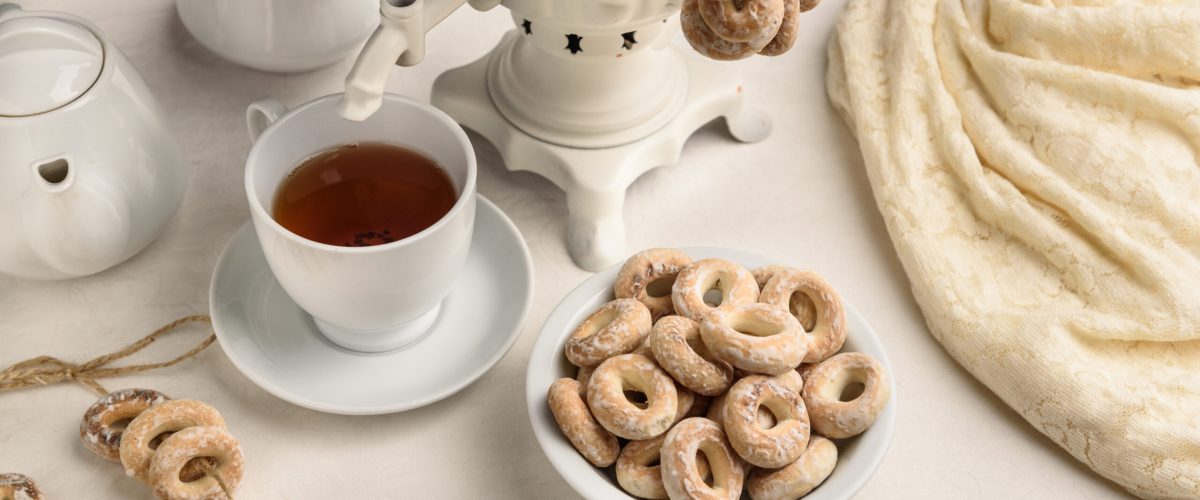 a samovar with bagels and hot tea on the white tablecloth