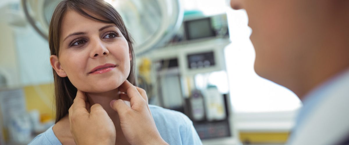 Doctor examining a female patients neck in the hospital