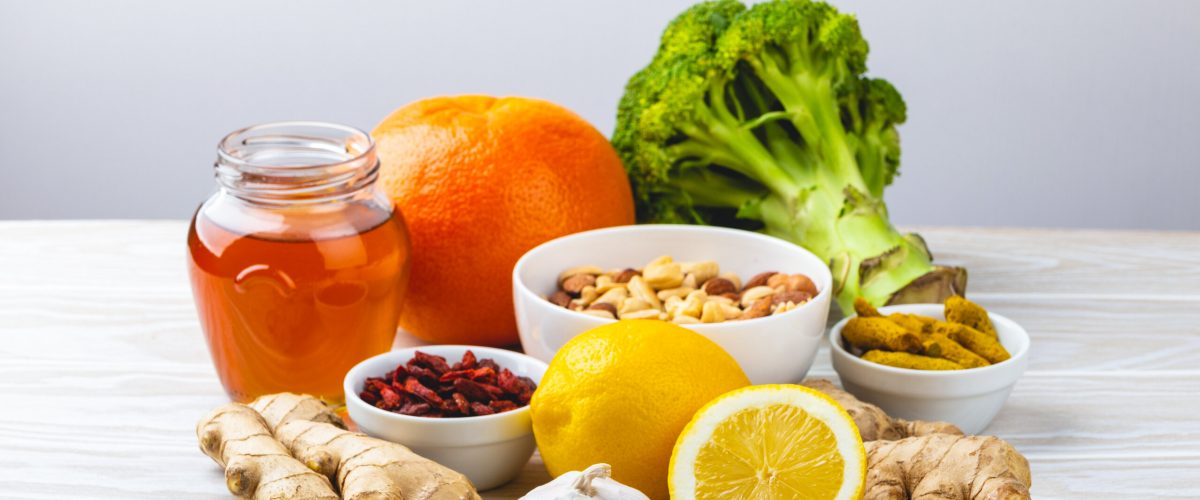 Food for immunity stimulation and viruses protection. Broccoli, citrus fruits, honey, ginger, lemon, garlic, goji, turmeric on white wooden background. Healthy natural food to boost immune system