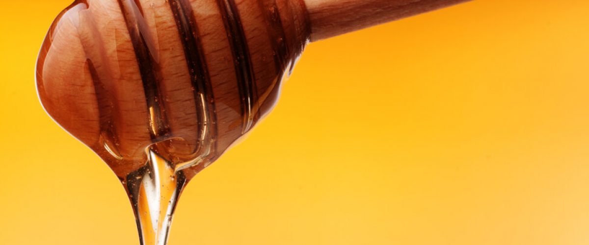 Honey dripping from a wooden honey