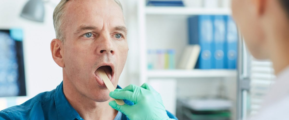 Close up portrait of mature man opening mouth during throat examination in clinic, copy space