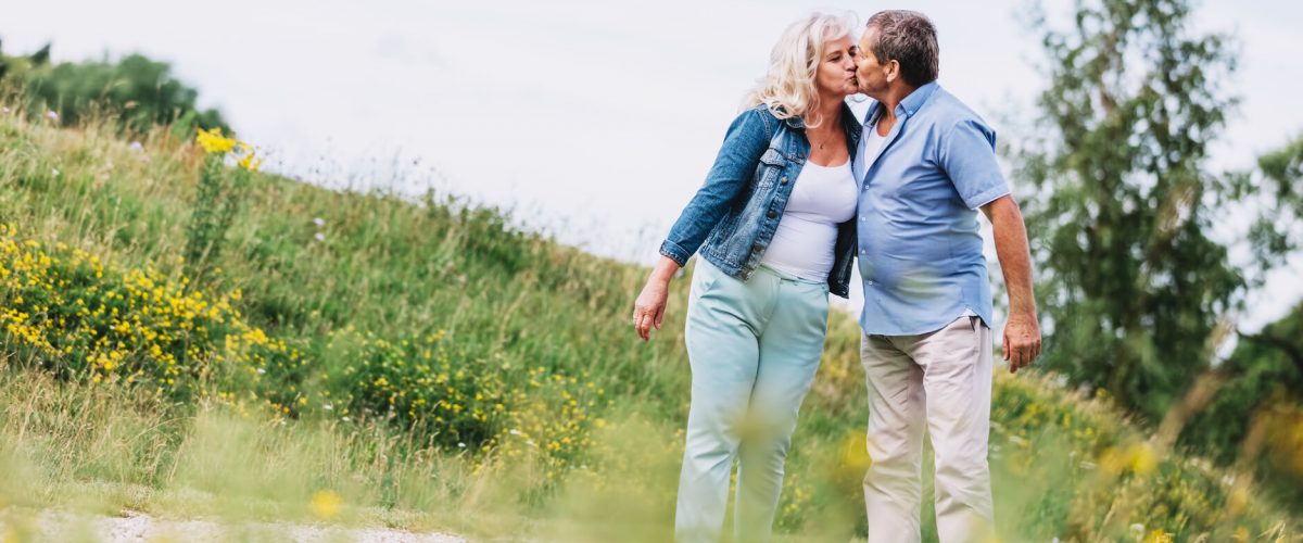 Old couple kissing on a walk. Elderly people retirement activities.