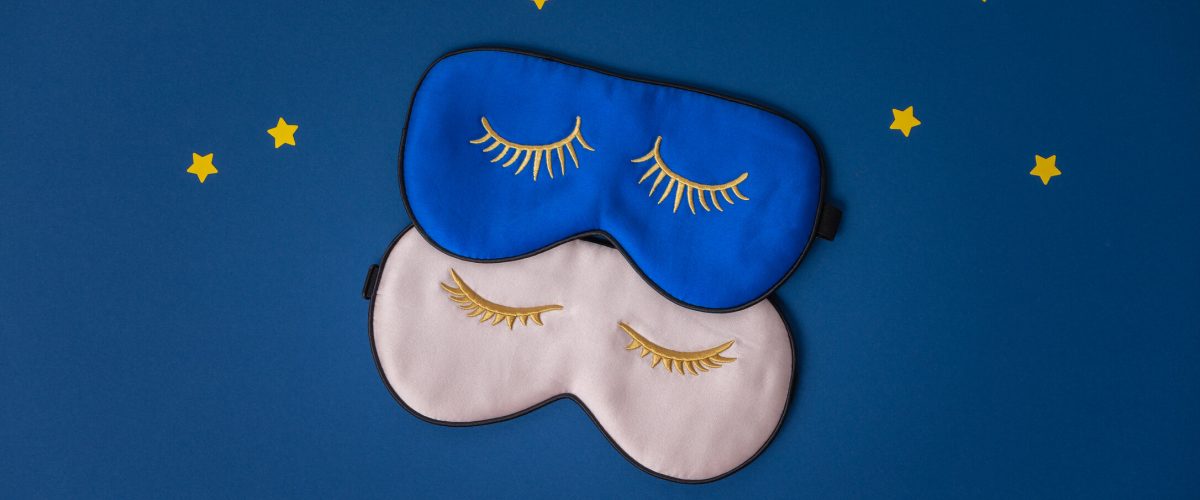 Two sleeping masks and paper stars on blue background, copy space, flat lay, top view